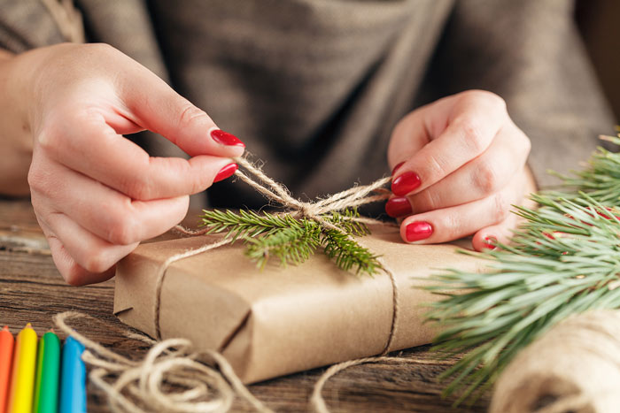 A lady tying string around a brown paper wrapped present to show it's possible to do Christmas on a budget.